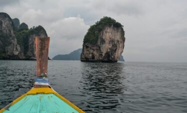 blue and brown boat on sea near brown rock formation during daytime