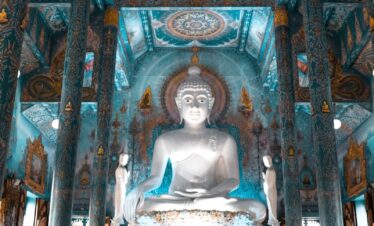 person kneels near Buddha